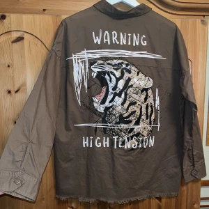 Tjock skjorta/lätt jacka - Tjockt skjortmaterial/lätt tunn jacka med print på baksidan! Verkligen aldrig använd förutom när jag tog första bilden, cool men inte min stil därför säljer jag den ❤️ Står XS/S som storlek, men då den är oversized & lång skulle jag vela säga strl S🐯