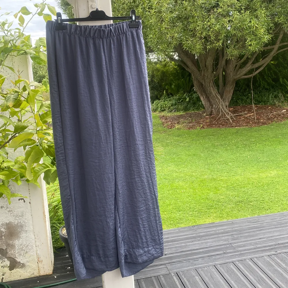 En pyjamas i ett tunt skönt tyg, byxorna kan man välja att ha högmidjade eller vika ner till lågmidjade, de är vida i benen, skortan är lite oversize, de är blå/gråa i färgen . Skjortor.