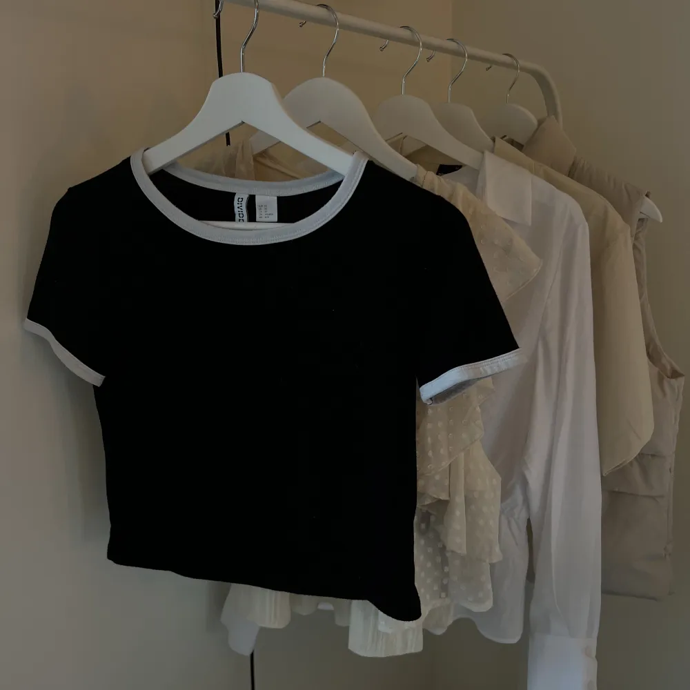 Svart kortare t-shirt från h&m med vita detaljer i strl XS. T-shirts.