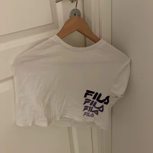 T-shirt - En fila tröja som är lite pytte lite slapp magtröja helt vitt och ett hörn där det står fila med lila bokstäver 