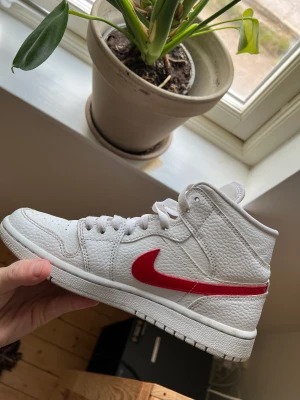 Nike Jordan 1 mid - Jordan 1 Mid White University Red storlek 38  De är använda knappt 2 månader Det är några sprickor vid sidan av ”tån” på den högra. Kvitto finns ej. 