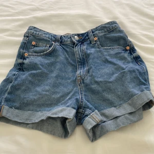 Jeansshorts - Blå högmidjade jeansshorts. Har två isyda hål. Fast de syns knappas.