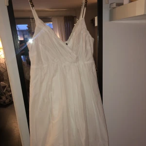 Vit kort klänning från Lindex  - Vit kort klänning från Lindex. Broderier längst ner och pärlor uppe på banden. Perfekt för student skolavslutningen eller bara när som i sommar. Passar xs-m.