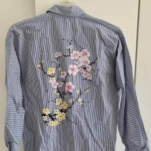 Blå/vit randig skjorta med broderade blommor på baksidan. Från Zara, storlek S. Knappt använd