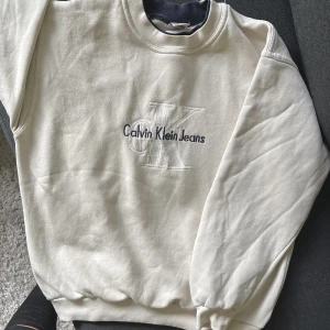 Calvin Klein collagetröja med dubbla tyg runt halsen  - Helt ny tröja.  Skickar bättre bilder vid intresse. Använd 1 gång storlek M funkar för herr också, nypris cirka 800-1000kr (minns inte exakt) 