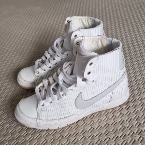 Sneakers Nike  - Ett par vita sneakers från Nike i lite glansigt "plastigt" material. Dom är ca 14-15 år gamla men har bara använts ett fåtal ggr och sedan stått i min garderob. 