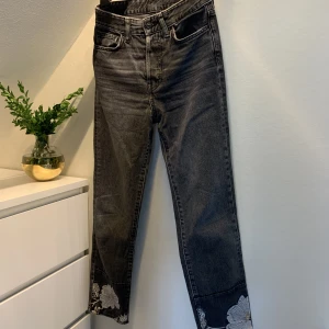 Svarta Jeans med Blomdetalj - Svarta jeans med broderade blommor vid anklarna. Tjockt och slittåligt tyg.