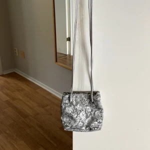 Axelremsväska  - Banden är ganska långa. Den är en fin blommig väska. 