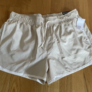 Badshorts nya  - Beiga med vita detaljer  Har fickor  Nya, oanvända med lapp kvar