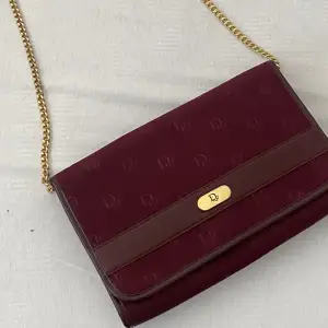 oroligt fin vinröd vintage väska från dior.   Jätte fin och bevarad väldigt bra.   Den kan användas som kuvert och crossbody väska.   Behöver bara fixa knappen gör stänga väskan hos skomakaren