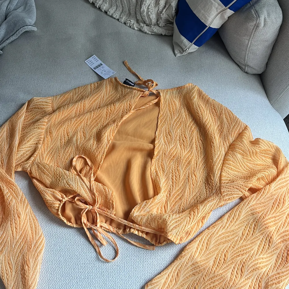 En orange blus från Gina tricot med öppen rygg och knytning, lapparna är kvar och är aldrig använd.. Blusar.
