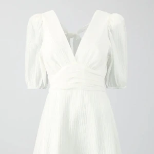 Vit klänning - Vit mini klänning ifrån Gina tricot med öppen rygg med knytning. Storlek 34. Oanvänd med prislapp kvar. 