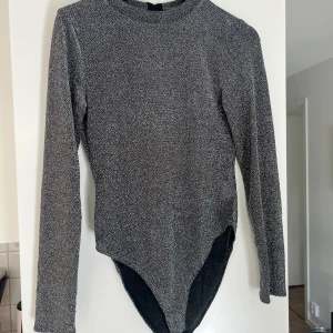 Glittrig body - Glittrig body med öppen rygg, sitter super fint på!  Storlek M Plagget finns på fler sidor så kan säljas. 