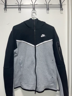 NIKE TECH FLEECE GRÅ / SVART - Säljer denna tröja då jag känner att den inte passar till min stil längre, tröjan har inga hål eller andra flaws och är inpirncip i nyskick.  Strl: Small 