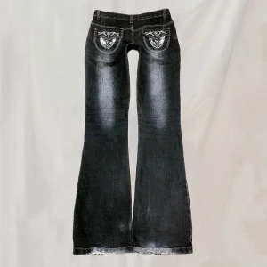 Jeans - Midja:76 innerben:82 jeans med detaljerade bakfickor. Sitter midwaist. Ganska grå-blå färg. Inga knappar på fickorna men verkar ska va så. Nötningar vid baksida fotändar. Saknas några enstaka paljetter, pärla. (Mer info kommentarer)🤍