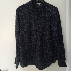 Mörkblå Prickig Lindex skjorta storlek L  - Mörkblå Prickig Lindex skjorta storlek L   Endast andvänd på en inspelningsdag  Obs, hund finns i hemmet   Fraktas enligt överenskommelse. Frakten bekostas av köparen.  PRISET GÅR ATT FÖRHANDLA