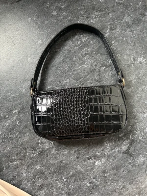 Svart axelarms väska - En svart axelväska från ginatricot