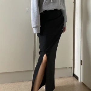 Långkjol - En långkjol i kostym-material. Den har en dragkedja där bak så den är lätt att få på. jag är 170cm lång och den släpar i marken. Finns ingen storlekslapp men skulle säga storlek 38. Jag är vanligtvis 36/38 och denna är lite lite stor. Oanvänd 