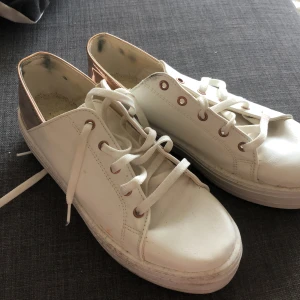 Vita sneakers med Roséguldkant  - Vita sneakers med Roséguld-kant. Storlek 38,5  Använd endast ett fåtal gånger. Några få fläckar syns men det är enkelt att ta bort, annars är de så gott som nya!