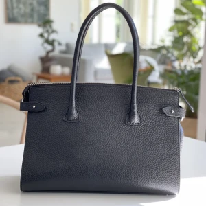 Decadent copenhagen - Scarlet handväska - Nypris ca 5300kr. I jätte fint skick!  Rymlig och fin handväska i läder. - fötter av metall - stängs med blixtlås - två läder handtag (17 cm) - rymligt huvudfack, lämpligt för a4 underlag - en ficka med dragkedja - två fickor  Storlek 35 x 24 x 15 cm (bre