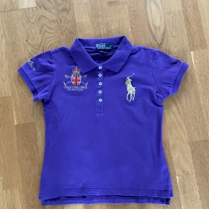 Polo Ralph Lauren Team Challenge Pikétröja  - En Lila Sällsynt Retro Ralph Lauren piké i storlek Barn Large/ XXS. Ganska ny hade den i ungefär tre månader innan jag växte ur den men inga hål eller något liknade, tröjan är precis som ny.