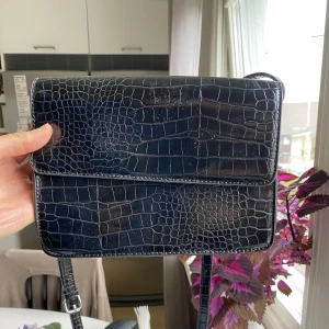 Svart handväska - Svart handväska i skinnimitation från märket Pieces. Perfekt storlek och rymmer det viktigaste, ex. Mobil, laddare, hörlurar etc. Sparsamt använd och i bra skick! 