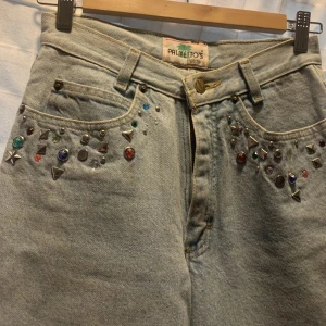 80-tals jeans - Högmidjade jeans med färgglada stenar på fickorna. Lite 80-tals stil på dom då dom ser lite ut som mom jeans. Använd kanske 3 gånger för 3 år sen.