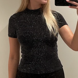 Glittrig topp - Svart glittrig t-shirt-topp från Monki i nyskick, storlek xs ✨Stretchig & supersnygg, perfekt till fest/nyår 