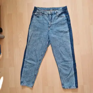 Mom jeans från monki i en tvättad blå färg, med mörkare blå ränder längs utsidan benet. Strl 30 enligt lappen (S/M).