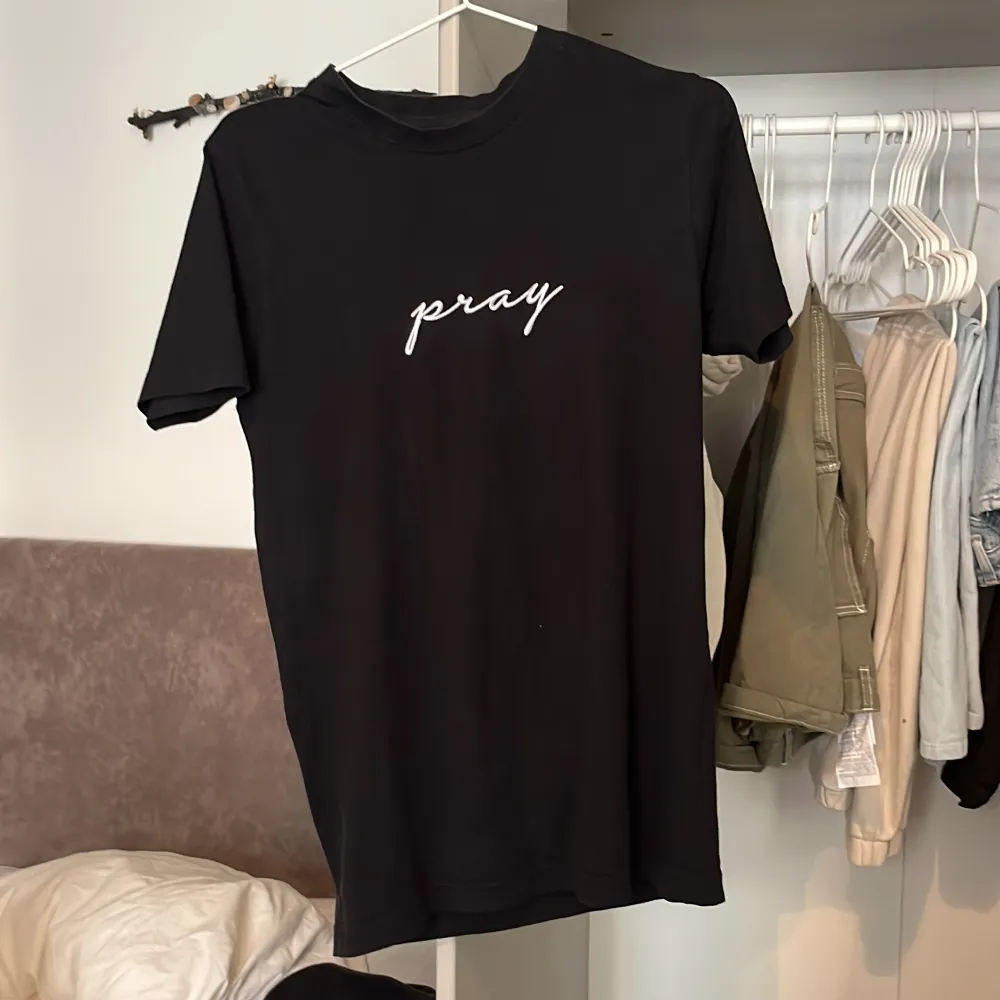 Svart T-shirt med trycket ”pray”. Storleken är xs.. T-shirts.