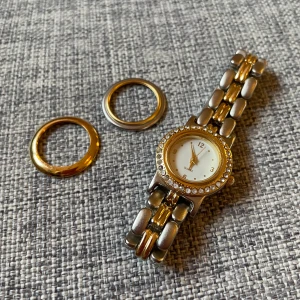 Damklocka med utbytbar framsida - En damklocka i nyskick, få rätt klocka för rätt tillfälle med justerbar bling-nivå via utbytbar framsida av boetten, se bild. Behöver nytt batteri.