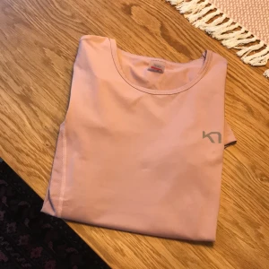 Billig rosa träningst-shirt - Använd cirka 3 gånger, alltså väldigt bra skick. Tränings tröja i ljusrosa. Ganska lång modell, nytvättad och i storlek XS🥰 från Karitraa.
