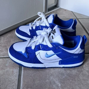 Nike Dunk low disrupt 2 white university blue - Nike dunk i fint skick knappt använda. Några små tecken på användning men gissar att det går att tvätta bort. Köpta för 2200 kr
