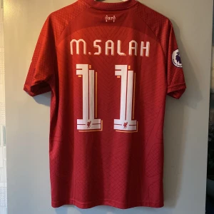 Salah Liverpool M - Fin tröja som jag fick av en kompis men som tyvärr inte passade. Den är i storlek M och i väldigt bra skick. Kan tänka mig gå ner lite i pris. Hör av er vid några frågor!