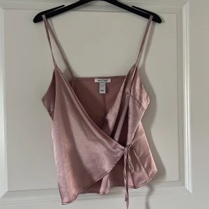 Topp - En rosa satin topp med omlott knytning.
