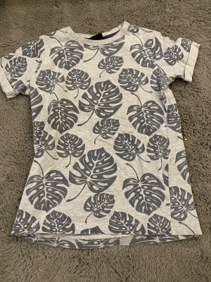 T-shirt - En T-shirt med blad mönster. Jag vet inte vad stl 9/10 betyder men jag skulle säga att den passar för 11-14 åringar