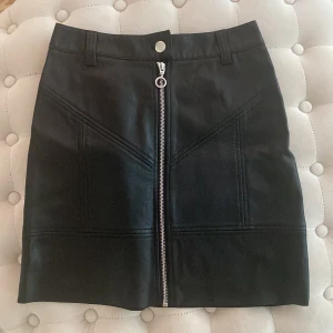 Skinnkjol  - Kort kjol, skinnimitation. Storlek 34 (uk 6). Högmidjan och figurnära. Aldrig använda, utan skavanker 