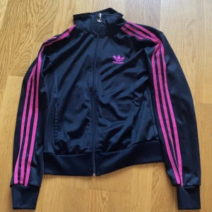 Adidas jacka  - Säljer en svart adidas jacka med rosa ränder. Den har inga tydliga defekter och är i superbra skick 300kr fri frakt 