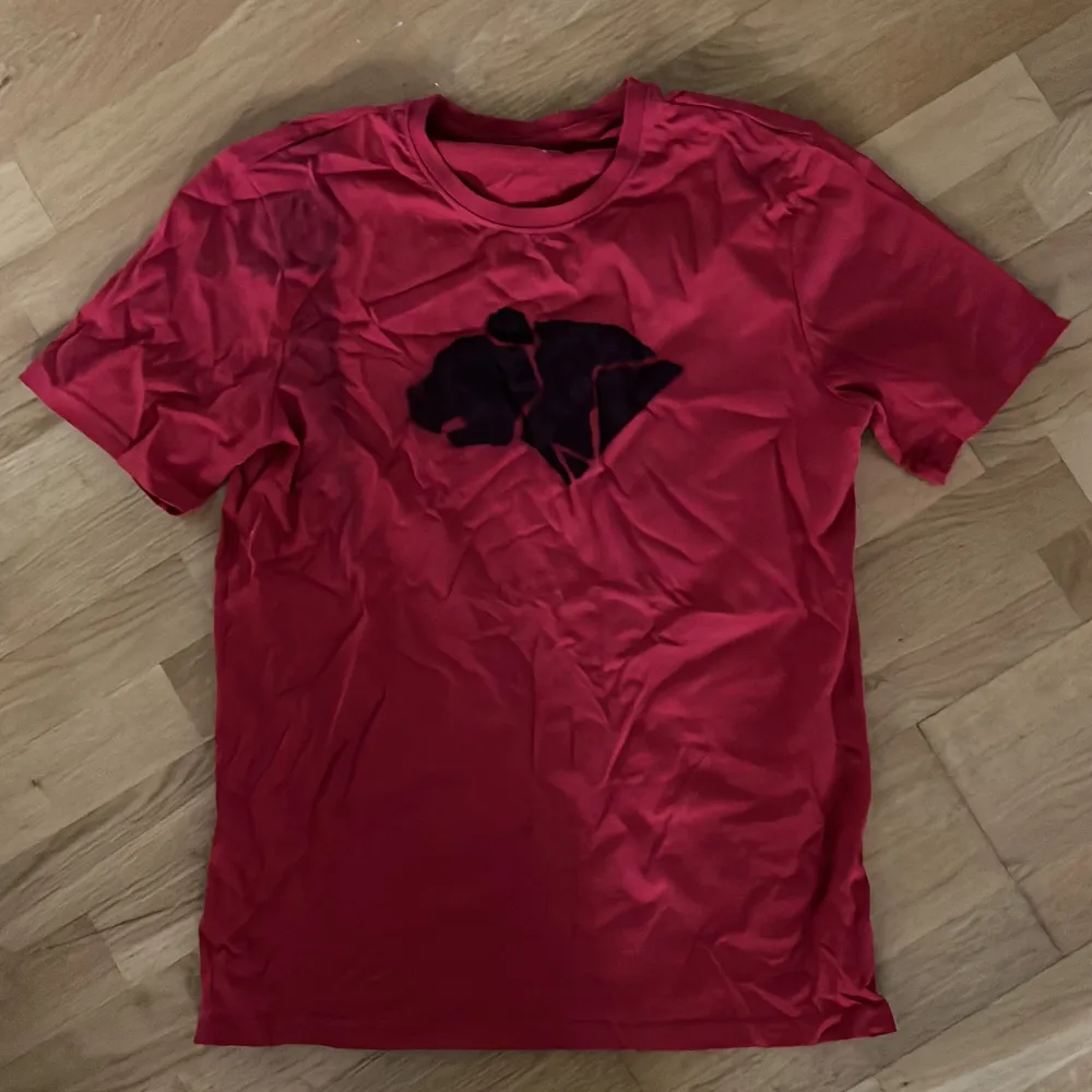 En enkel oanvänd röd t-shirt med ”björnarna” loggan från Wildkids! En superenkel utklädnad till halloween, du behöver bara lägga till lite svarta streck på kinderna 😍   OBS det är lite svart sprayfärg i hörnet på ena ärmen från när jag sprayade den :). T-shirts.