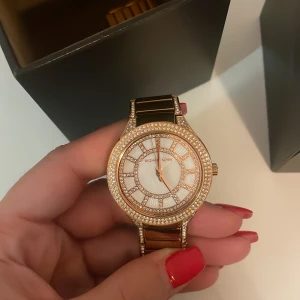 Michael kors klocka - Säljer Michael kors klocka som inte kommer till användning längre, superfin i guld med strass både utanpå och innanför. Kommer även med extra ”länkar” till klocka för att justera om man vill göra den större. 