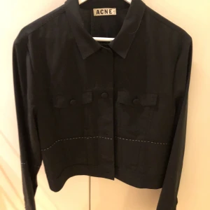 Acne kostym  - Använd 2 gånger. Kort kavaj med vita små kontrast stygn likadant på byxorna. Normal i storleken. Behöver inte strykas. Båda måste köpas tillsammans. Kavaj 2300kr och byxa 1500kr. 