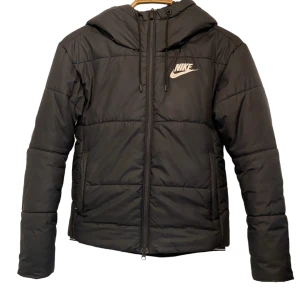 Nike vadderad jacka  - Vadderad jacka Nike. Mudd i ärmslut och nederkant på jackan. Huva och bra fickor.  Kan skickas. Köparen betalar då portot.  