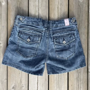 Y2k Shorts - Sjukt snygga shorts med häftiga fickor. Knapparna har gulliga mönster. Mycket god kvalitet på shortsen.  De är för små för mig så kan tyvärr inte bifoga bild med dem på person, men måtten är: Midja (tvärsöver): 38cm Lår (tvärsöver): 27cm Längd: 30cm