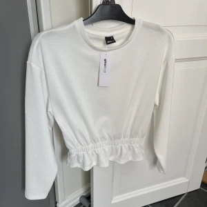 Topp - Vit topp från Gina Tricot i storlek XS. Aldrig använd, lappen sitter fortfarande kvar. Nypris 259kr, mitt pris 120kr plus frakt. Har mycket fler plagg ute tillsalu! 
