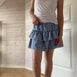 Volangkjol - Fin volangkjol med blommigt mönster, sparsamt använd men ett litet hål (se på bild 3) enkelt att fixa med lite tråd💙hör av er om ni undrar något!