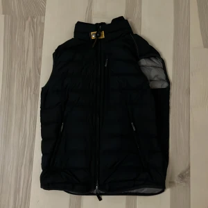 Parajumper väst - Säljer den för att den är för liten. Den är sparsamt använd och den enda defekten är ett litet hål i ena fickan. Jag har kvar tags som visar på att den här äkta, kvittot finns dock inte kvar. Nypris 3000kr