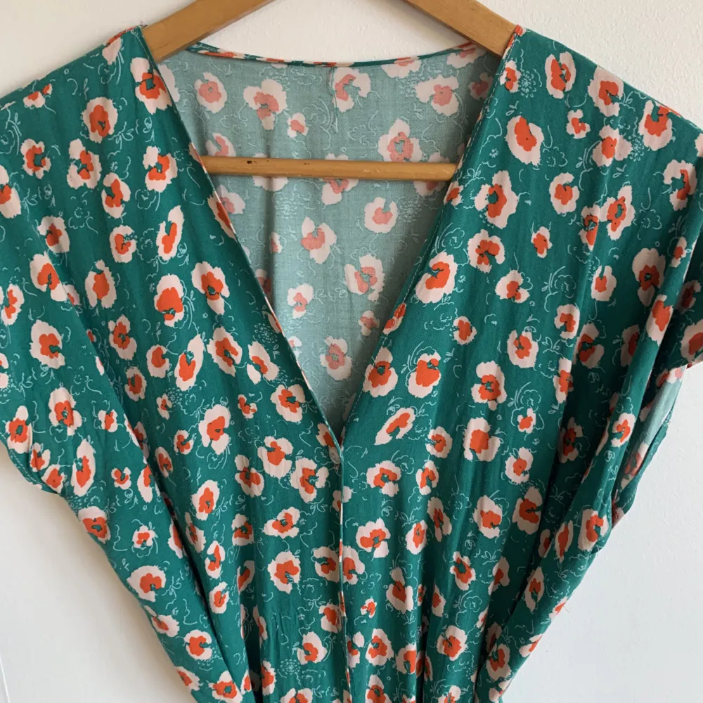 Blommig långklänning. Med skärp och knappar framtill i viskos. . Mekot.