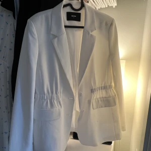 Vit kavaj med midja - Vit kavaj i fint skick,använd 2 gånger. Har en fläck på axeln då den inte är tvättad, men den går bort!