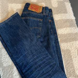 Jeans i modellen 501 Levi’s. Inga defekter, knappt använda. Nypris över 1000kr. Storlek: Waist 28 length 32. Jag brukar ha 36 i jeans och dessa passar mig bra. Mörkblåa.