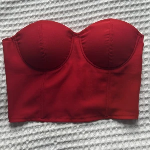 Röd korsetttopp - Jättefin korsetttliknade topp! Ganska ostrechigt material med silikon vid brösten så att den inte halkar ner. 